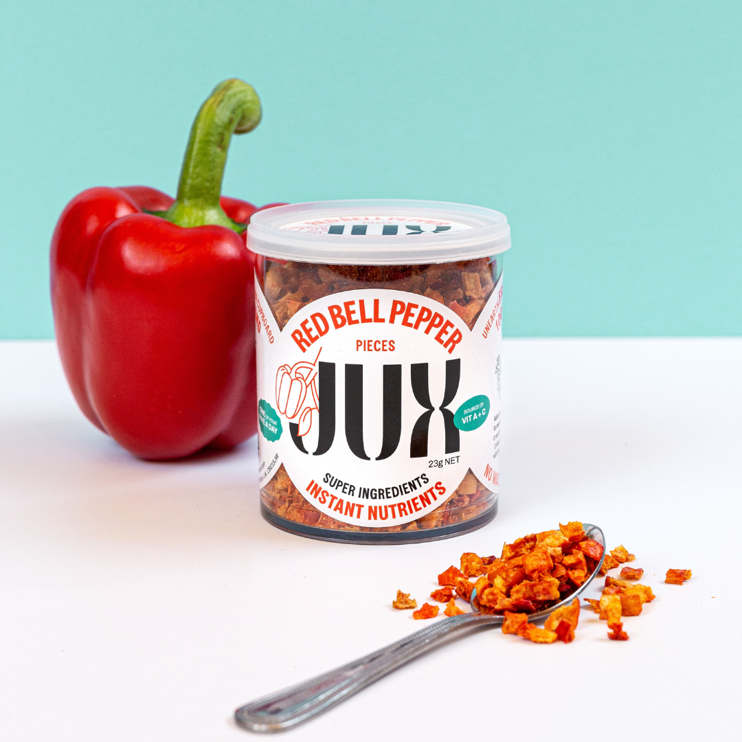 JUX Freeze-dried chopped Red Bell Pepper pieces in pot and on a teaspoon next to a fresh red bell pepper