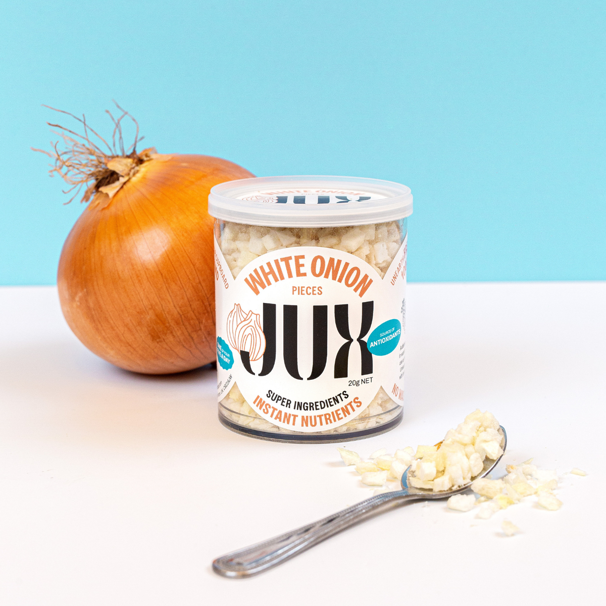 JUX chopped Freeze-dried White Onion in its pot and on a teaspoon next to a fresh onion