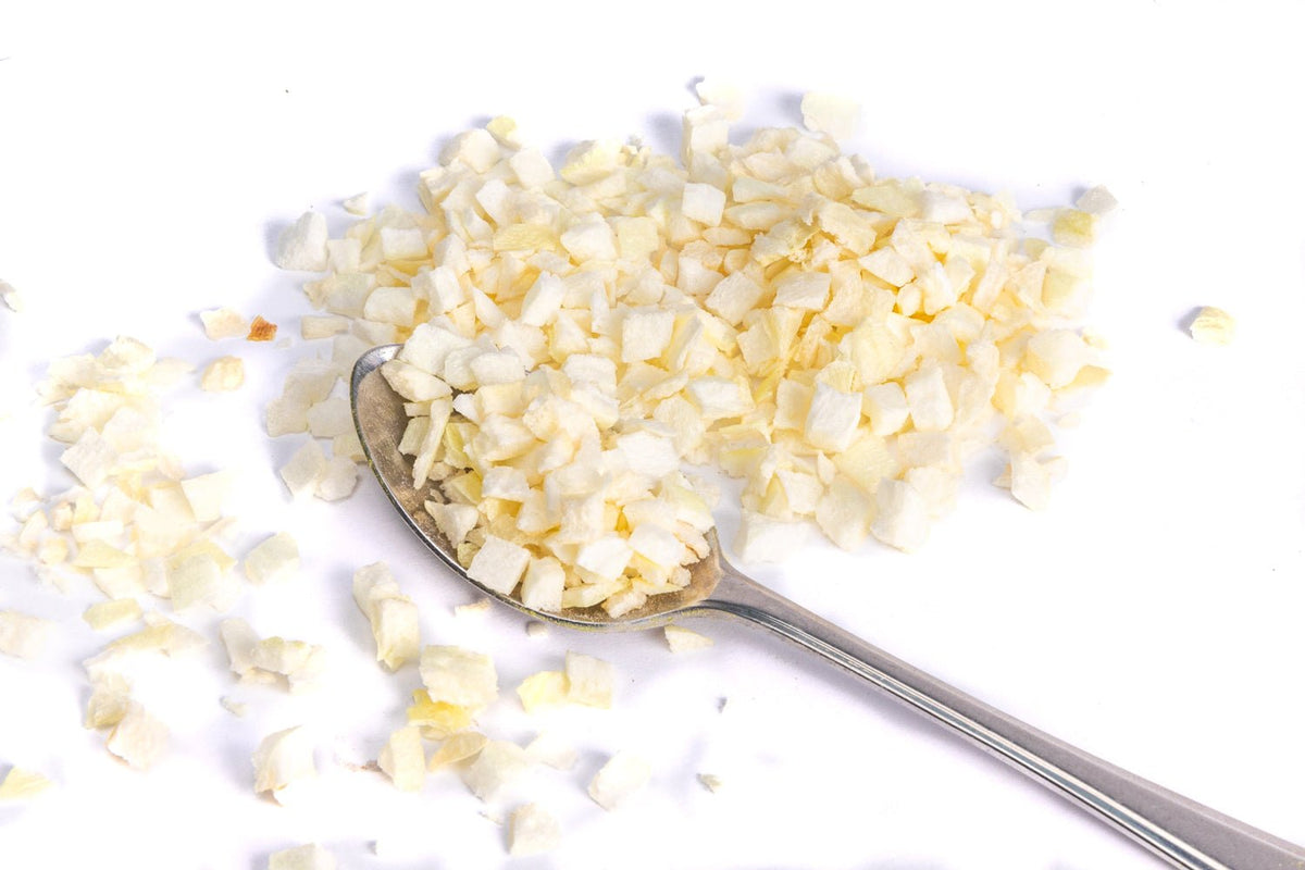 JUX freeze-dried chopped white onion pieces on a teaspoon
